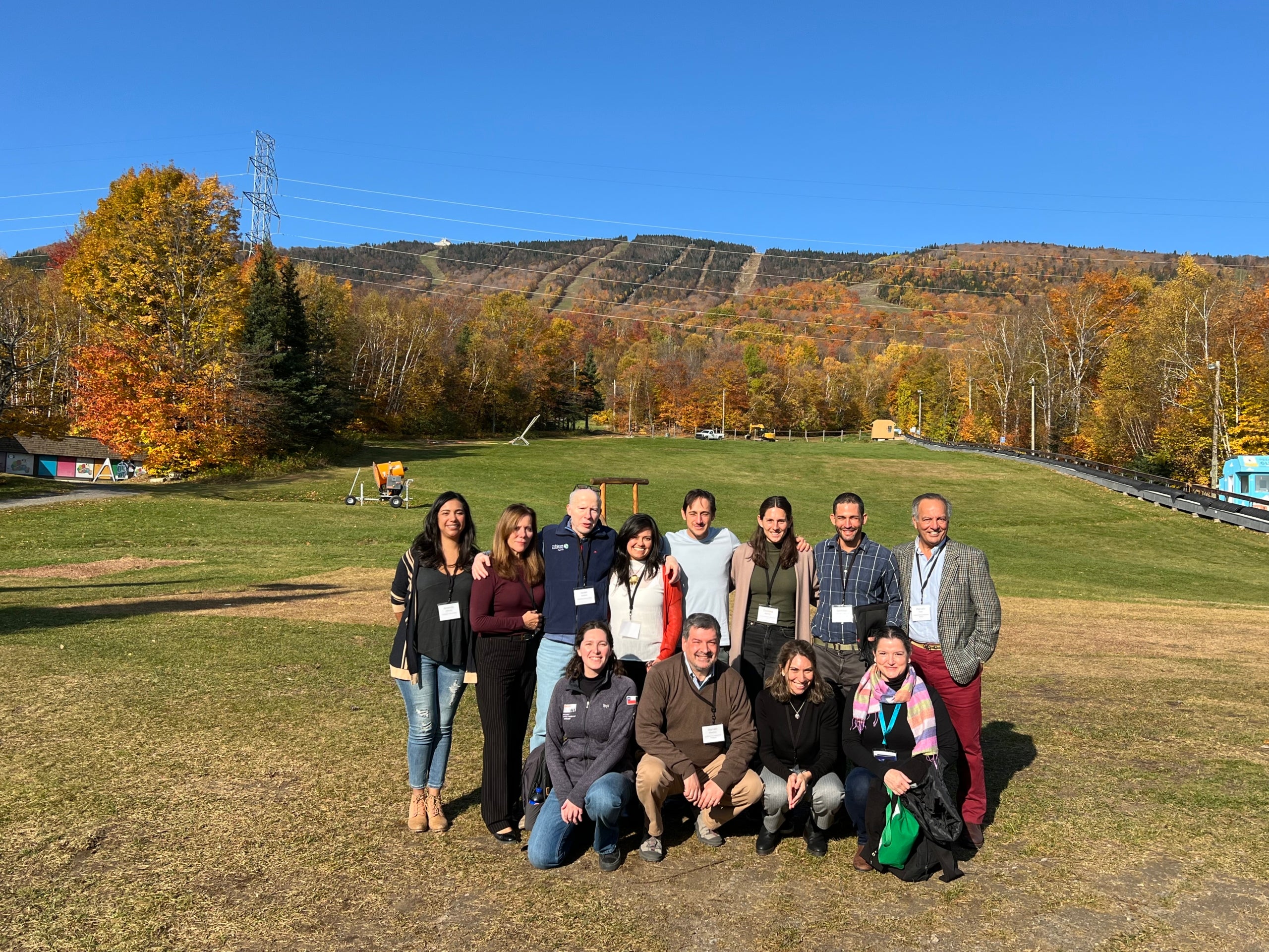 A group of 12 people post on outside at an off-season ski resort. 