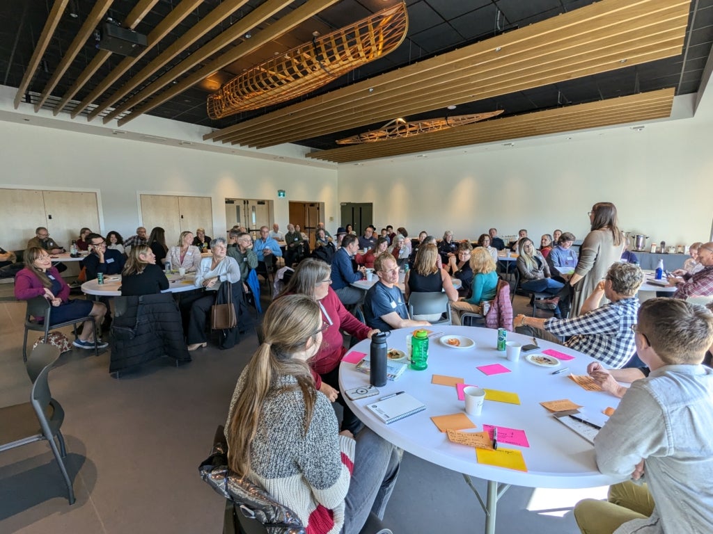 People sit around tables in a large conference room at a kickoff event for the Kawartha Resilient Lands Collaborative.