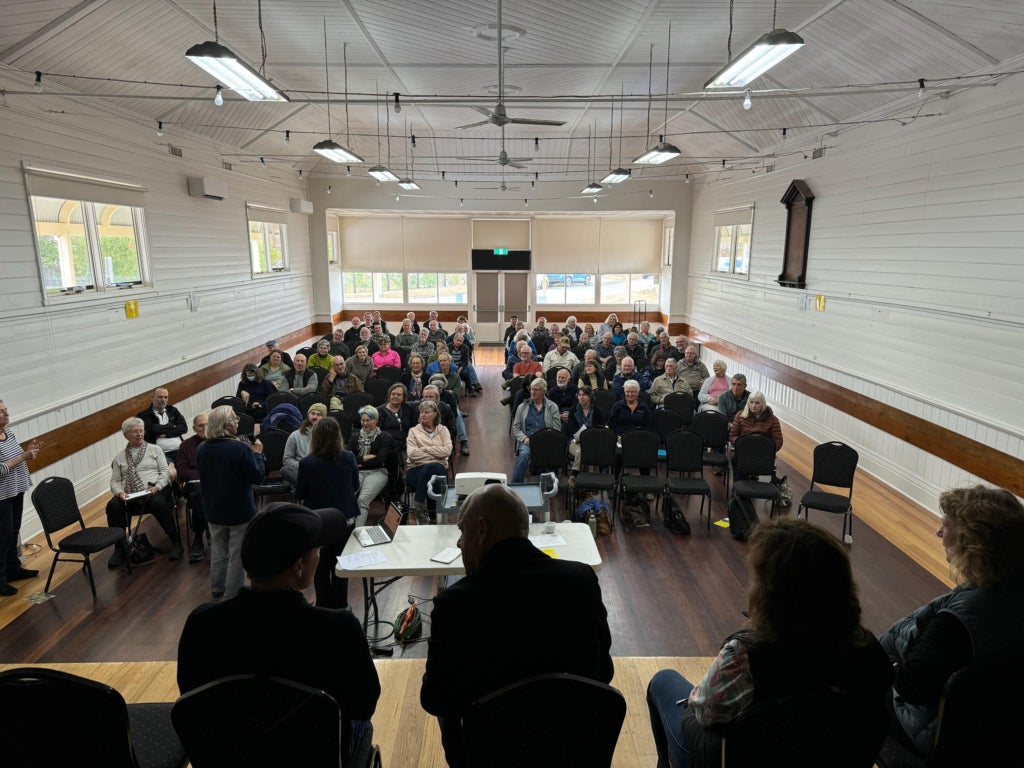 A group of conservationists sit in chairs, gathered in front of a panel of speakers.