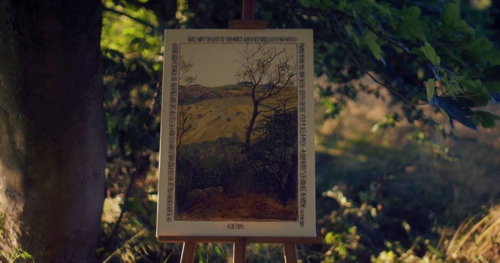 A canvas stands on an easel beneath a tree. It is painted with a landscape using egg tempera. A wide border is filled with stylized prose telling a story of the artist's emotional connection to the region's suffering trees.